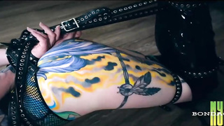 Tatted dark haired in hip high shoes with high high-heeled shoes is about to get corded up and ball-gagged