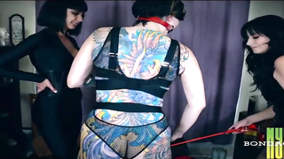 Tatted dark haired in hip high shoes with high high-heeled shoes is about to get corded up and ball-gagged