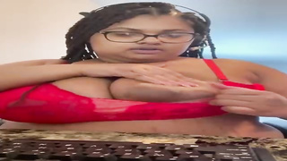 Big-Titted Ebony gal in softcore, crimson underwear is posing and taunting in front of the camera