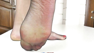 Hooded ash-blonde is showing her voluptuous soles in black nylons, with a bit of spunk on top