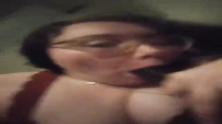 Nerdy honey is blowing a large, black salami in front of the camera, just for joy