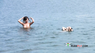 Nude beach girl sunbathes next to her man outdoors