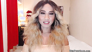 Asain blonde TS wanks cock in chair in front of webcam