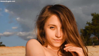 Captivating, nude stunner is loving on the beach and frolicking with her scarf during the sunset