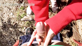 Pretty female in crimson is massaging her beau's fuck-stick in the nature, to make him jizz